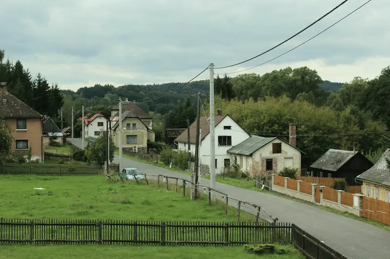 Dorfstraße mit Wohnhäusern und Freileitung